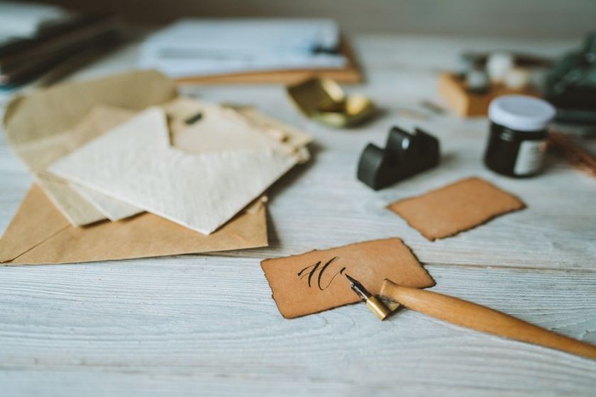 A folded letter on a writing desk beside a wax seal and a fountain pen